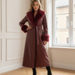 Abrigo largo de polipiel color burdeos con cinturón y cuello y puños de pelo sintético, combinado con botas altas negras.