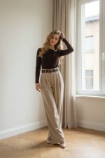 Camiseta de licra ajustada de manga larga color marrón chocolate con cuello redondo y broche decorativo metálico en el hombro.