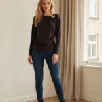 Camiseta de licra ajustada de manga larga color marrón chocolate con cuello redondo y broche decorativo metálico en el hombro.