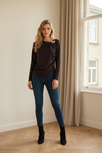 Camiseta de licra ajustada de manga larga color marrón chocolate con cuello redondo y broche decorativo metálico en el hombro.
