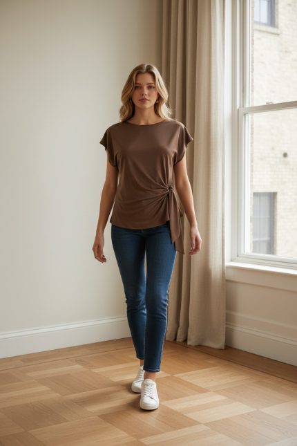 Camiseta marrón de manga corta con lazo lateral ajustable en el bajo, corte entallado, combinada con jeans ajustados.