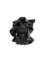 Chaleco negro de estilo vanguardista en material tipo cuero, con volantes estructurados, cremallera asimétrica y cinturón con hebilla, presentado sobre fondo neutro.