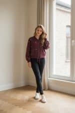 Chaqueta bomber corta color burdeos con cierre de cremallera frontal y bordados pequeños en forma de estrella en toda la prenda.