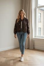 Chaqueta bomber corta color marrón con cierre de cremallera frontal y bordados pequeños en forma de estrella en toda la prenda.