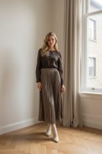 Falda midi plisada de color marrón con acabado satinado y caída fluida.