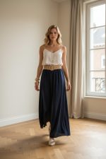 Pantalón fluido beige de tiro alto con pernera ancha, pinzas frontales y cinturón ancho a juego.