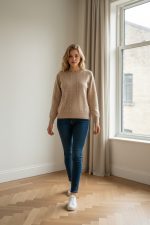 Jersey de punto color beige con manga larga y cuello redondo, decorado con pequeñas perlas distribuidas verticalmente en el frontal y las mangas.