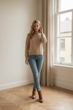 Jersey de punto color beige con manga larga y cuello redondo, decorado con pequeñas perlas distribuidas verticalmente en el frontal y las mangas.