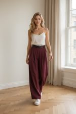 Pantalón ancho de vestir color burdeos de tiro alto con cinturón negro, combinado con top blanco y zapatillas blancas.