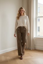 Pantalón vaquero recto de tiro medio-alto en color marrón lavado, con bolsillos delanteros de parche y corte largo, combinado con jersey claro y mocasines marrones.