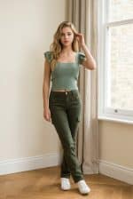 Top corto de punto acanalado en color verde con escote cuadrado y mangas cortas con volantes, combinado con pantalón cargo verde.